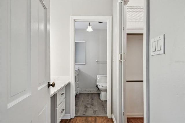 bathroom with toilet, wood finished floors, vanity, and baseboards