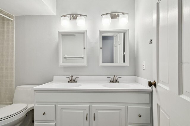 full bath with double vanity, toilet, and a sink