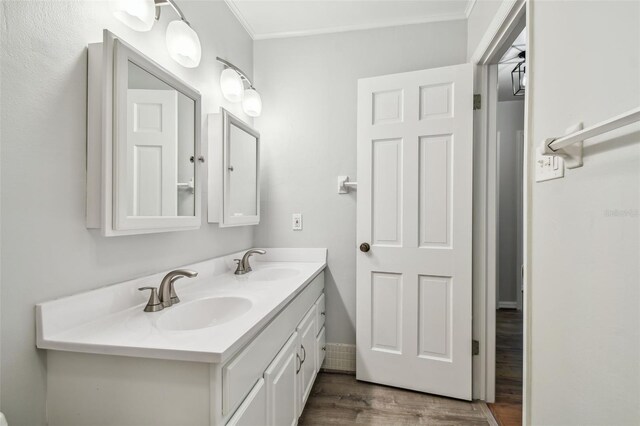 bathroom with ornamental molding, double vanity, wood finished floors, and a sink