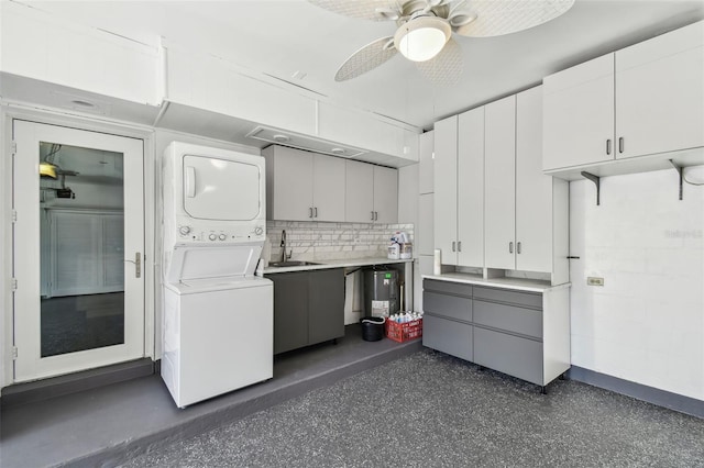 clothes washing area featuring stacked washer / dryer, a sink, and a ceiling fan