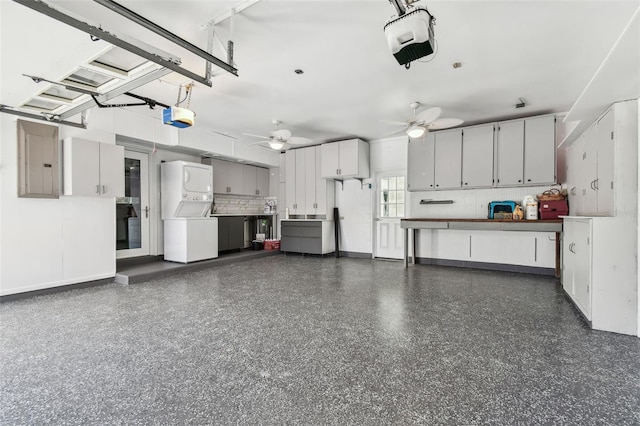 garage with ceiling fan, electric panel, stacked washer and clothes dryer, and a garage door opener