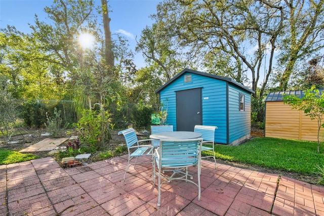 view of patio with a shed, outdoor dining area, and an outbuilding