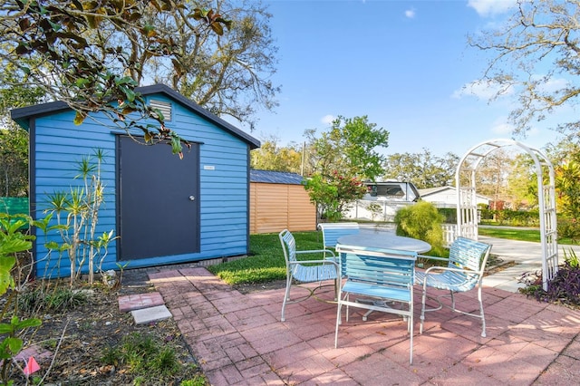 view of patio with a storage unit, outdoor dining area, and an outbuilding