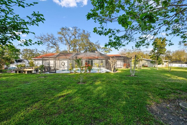 back of property featuring glass enclosure, an outdoor pool, and a yard