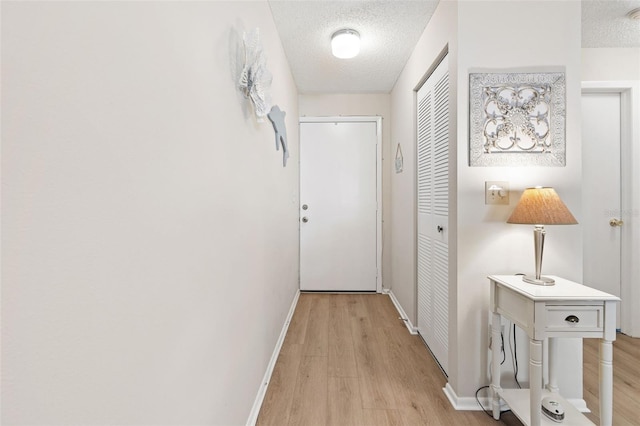 hall with a textured ceiling and light hardwood / wood-style floors