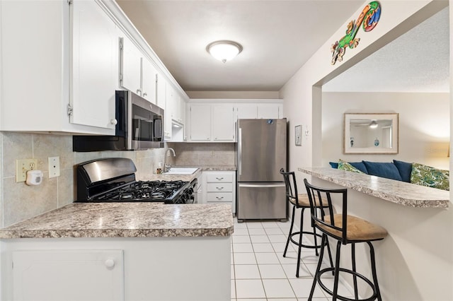 kitchen featuring white cabinetry, sink, stainless steel appliances, and kitchen peninsula