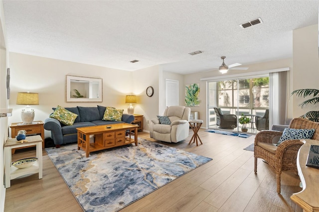 living room with ceiling fan, light hardwood / wood-style floors, and a textured ceiling