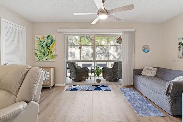 living room featuring a textured ceiling, ceiling fan, and light hardwood / wood-style flooring