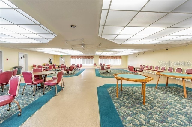 recreation room featuring ceiling fan, a paneled ceiling, and rail lighting