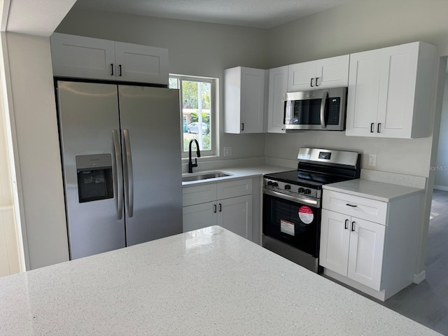 kitchen with sink, white cabinets, light stone countertops, and appliances with stainless steel finishes