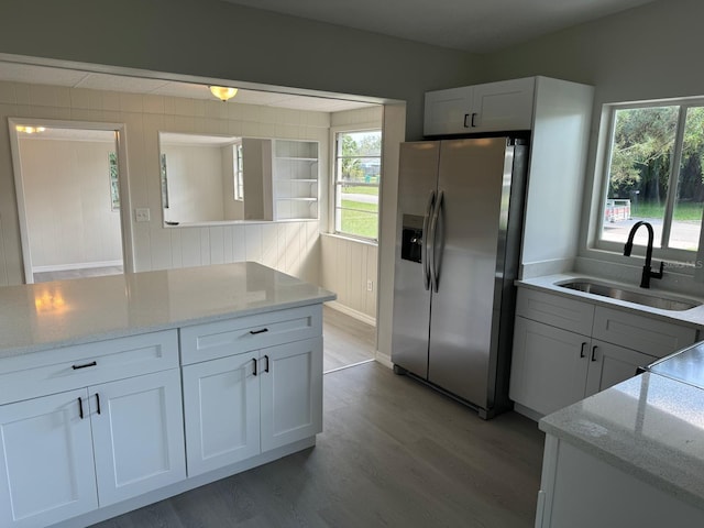 kitchen featuring sink, white cabinetry, stainless steel fridge, and light stone countertops