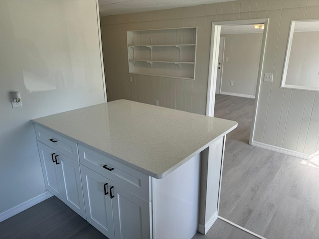 kitchen with built in features, white cabinets, light stone countertops, and light hardwood / wood-style floors