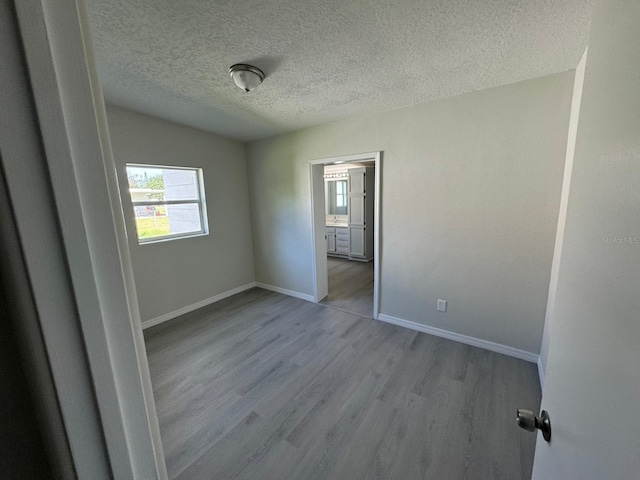 empty room with a textured ceiling and light hardwood / wood-style flooring