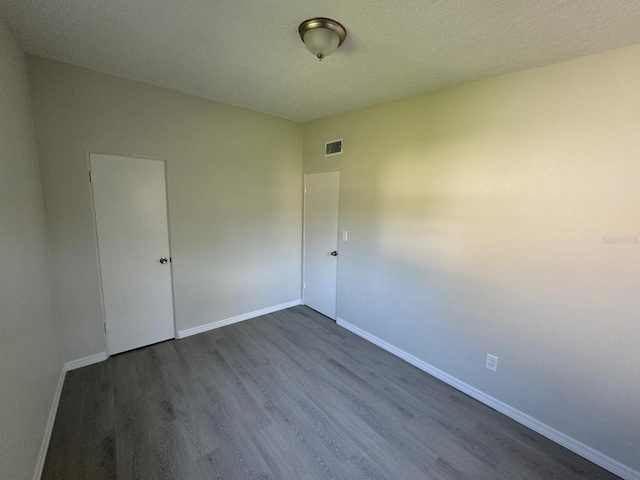 unfurnished room featuring a textured ceiling and dark hardwood / wood-style flooring