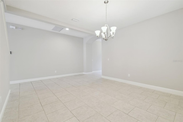 tiled spare room featuring a notable chandelier