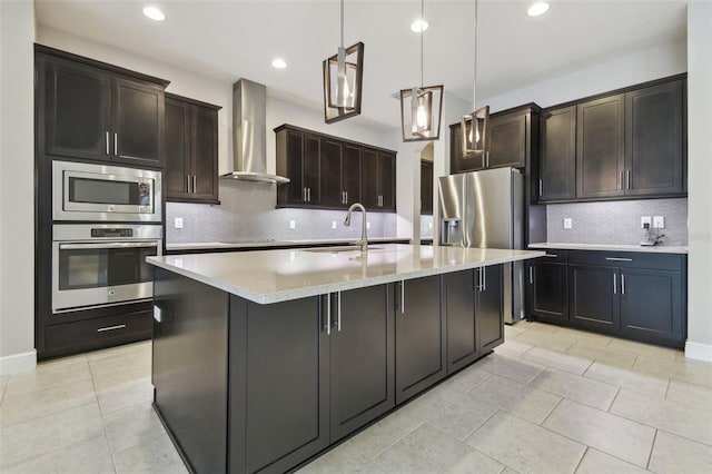 kitchen featuring dark brown cabinets, hanging light fixtures, appliances with stainless steel finishes, sink, and wall chimney range hood