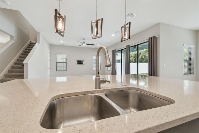 interior details featuring sink, hanging light fixtures, and light stone countertops