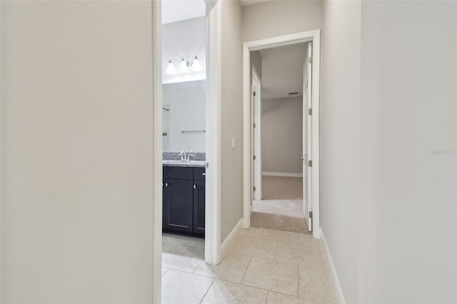 hallway featuring sink and light tile patterned flooring