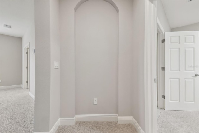 hallway with light carpet and vaulted ceiling