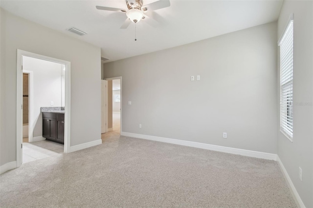 unfurnished bedroom featuring ceiling fan, ensuite bathroom, and light carpet