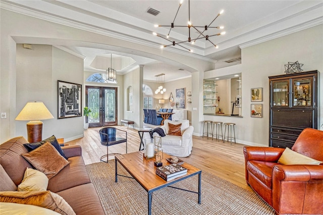 living room featuring french doors, crown molding, light hardwood / wood-style floors, and a notable chandelier