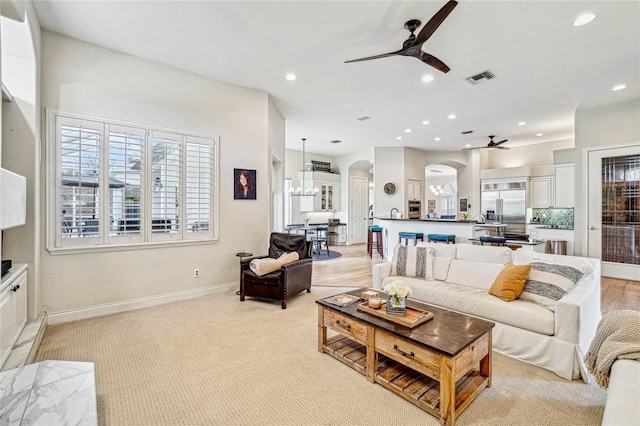 living room with light carpet and ceiling fan with notable chandelier