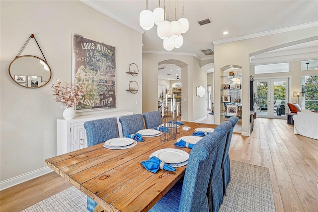 dining room with french doors, ornamental molding, a chandelier, and light wood-type flooring