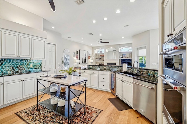 kitchen with sink, appliances with stainless steel finishes, kitchen peninsula, decorative backsplash, and white cabinets