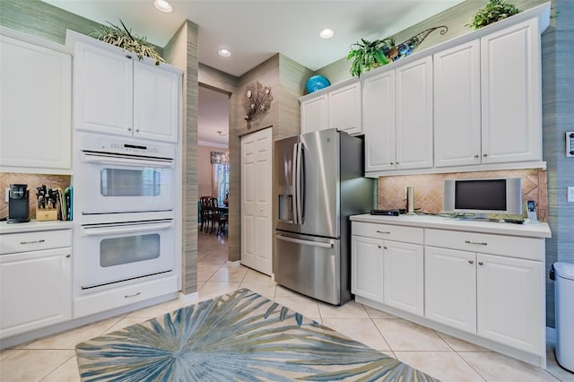 kitchen featuring stainless steel refrigerator with ice dispenser, tasteful backsplash, light tile patterned floors, double oven, and white cabinets