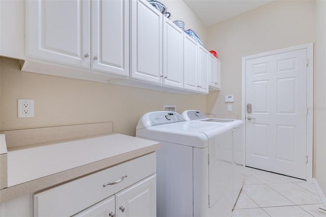 washroom with light tile patterned floors, washing machine and dryer, and cabinets