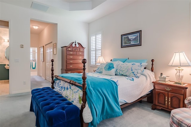 bedroom with light colored carpet and connected bathroom