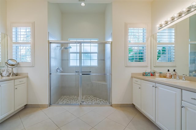 bathroom with a shower with door, vanity, and tile patterned floors