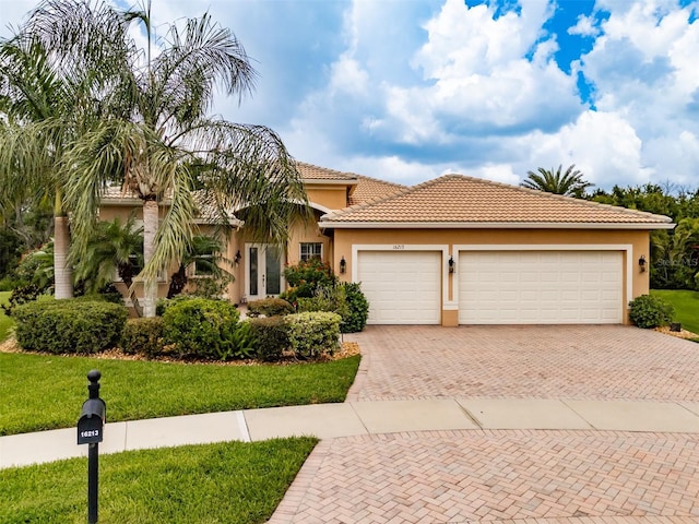 mediterranean / spanish home with a garage and a front lawn