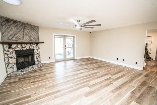 unfurnished living room with a fireplace, light hardwood / wood-style flooring, ceiling fan, and french doors