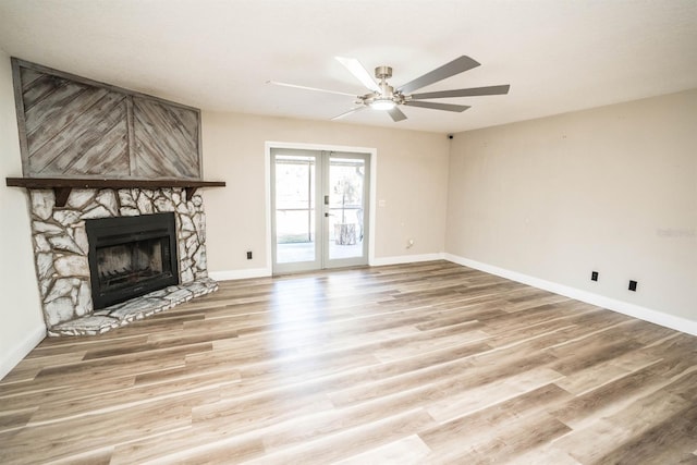 unfurnished living room with ceiling fan, hardwood / wood-style floors, french doors, and a fireplace