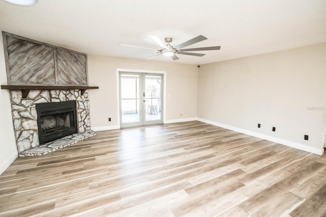 unfurnished living room featuring a fireplace, light hardwood / wood-style floors, ceiling fan, and french doors