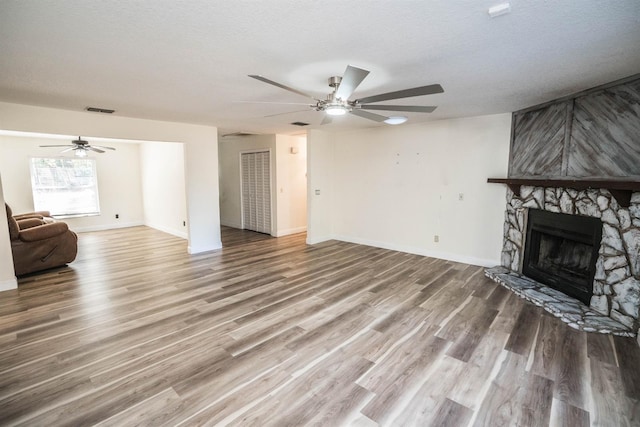 living room featuring wood-type flooring, a textured ceiling, ceiling fan, and a fireplace