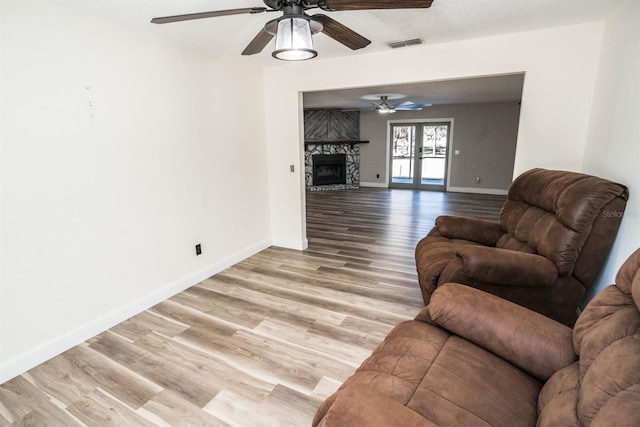 living room featuring light hardwood / wood-style floors, french doors, and a large fireplace