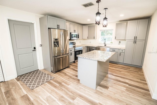 kitchen with a center island, light stone countertops, gray cabinetry, pendant lighting, and stainless steel appliances