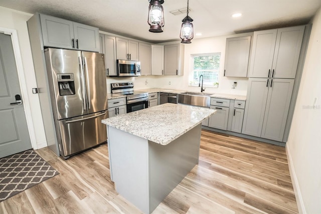 kitchen with pendant lighting, a kitchen island, stainless steel appliances, sink, and gray cabinets