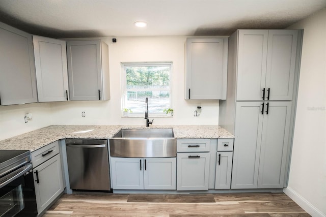 kitchen featuring stainless steel dishwasher, range with electric stovetop, sink, gray cabinetry, and light stone counters