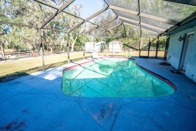 view of swimming pool with glass enclosure, a patio area, a water slide, and a shed