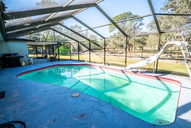 view of swimming pool featuring glass enclosure, a water slide, and area for grilling