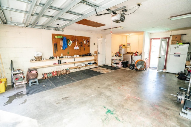 garage featuring washer and dryer, white refrigerator, a workshop area, and a garage door opener