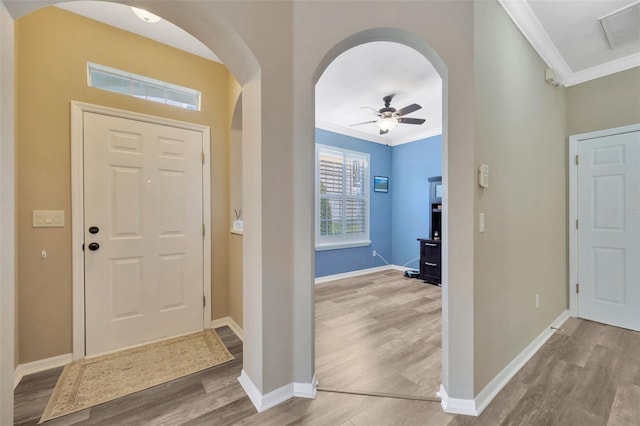 foyer entrance with crown molding, wood-type flooring, and ceiling fan