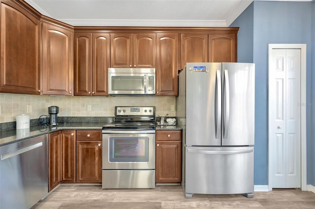 kitchen featuring backsplash, light hardwood / wood-style flooring, dark stone counters, and appliances with stainless steel finishes