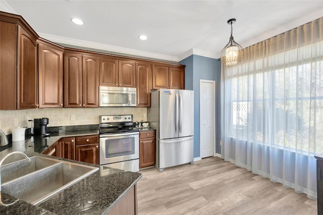 kitchen featuring appliances with stainless steel finishes, sink, decorative light fixtures, light wood-type flooring, and decorative backsplash