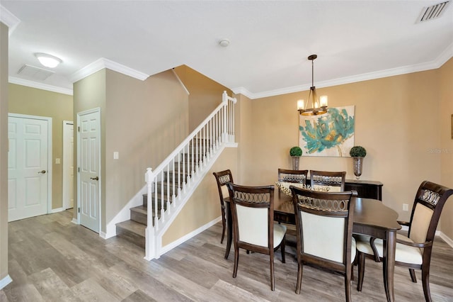 dining room featuring light wood-type flooring, crown molding, and an inviting chandelier