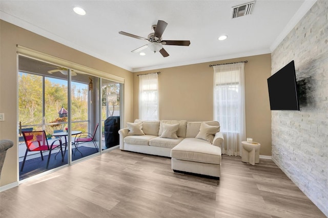 living room with light hardwood / wood-style floors, ornamental molding, and ceiling fan