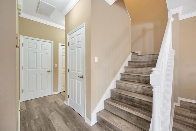 staircase with hardwood / wood-style flooring and crown molding